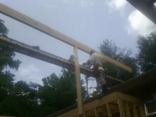 Carpenter setting a ridge beam over a new addition frame — Ice Dam Removal by Roofing Brothers in De Ruyter