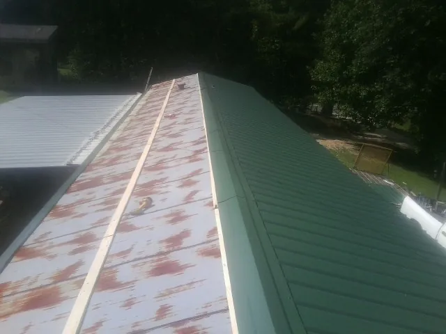 Old rusted panels beside newly installed green metal roofing — Wind Damage Roof Repair by Roofing Brothers in De Ruyter