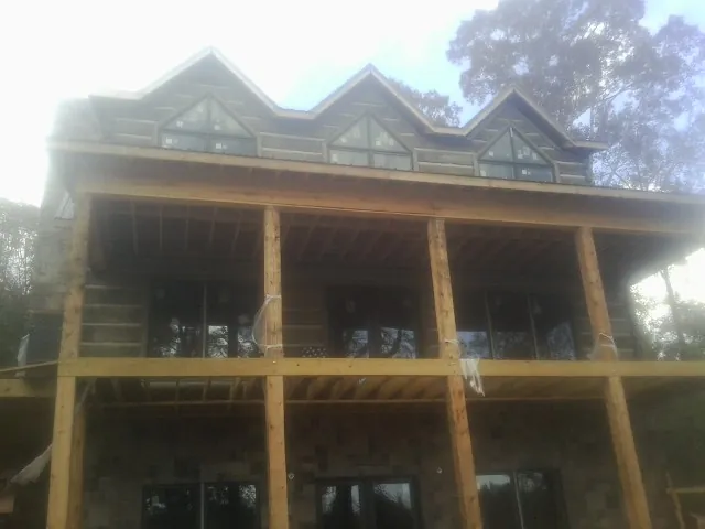 Dormers and porch framing on a large log home under construction — Roof Coating work by our crew in De Ruyter