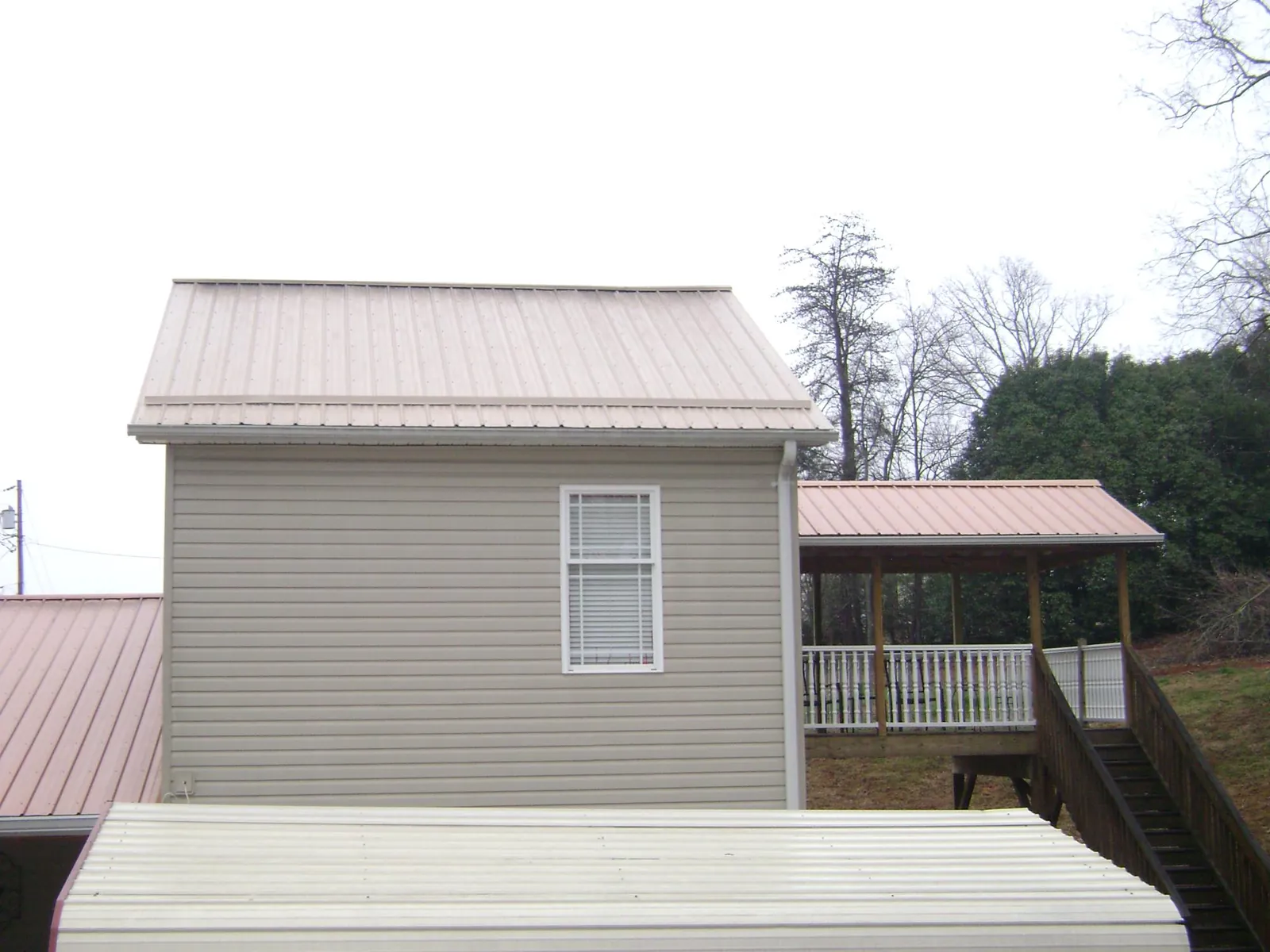 Tan metal roofs on a two story addition and attached porch, from a Roof Replacement job in De Ruyter