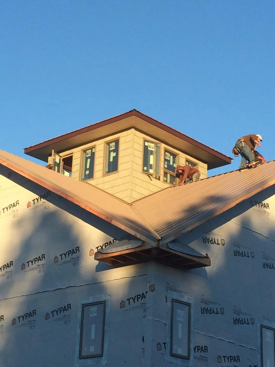 Roofers working around a rooftop cupola on a new metal roof at sunset — Roof Waterproofing in De Ruyter by Roofing Brothers